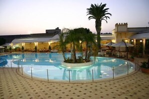 A swimming pool with a palm tree in the center, surrounded by lounge chairs and umbrellas. - Grand Hotel Palace (Marsala)