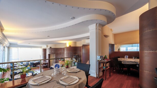 A restaurant with a curved ceiling, wooden flooring, and a table set for two with a beige tablecloth. - Residence Hotel Torino Uno (Turin)