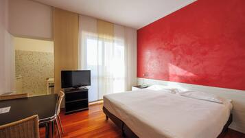 A hotel room with a bed, a TV, a desk, and a chair.