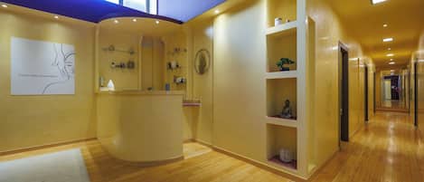 A hotel reception area with a wooden floor, a reception desk, and a wall-mounted artwork.