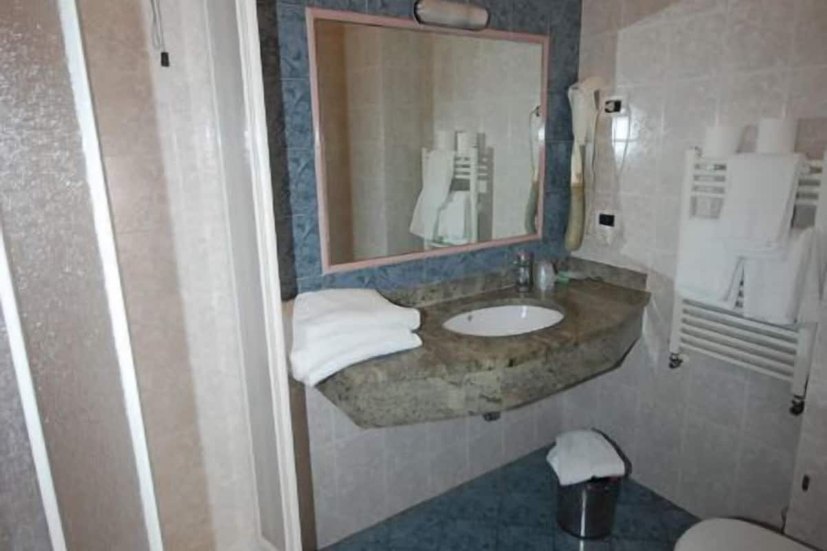 A bathroom with a shower, a sink, a mirror, and a toilet.