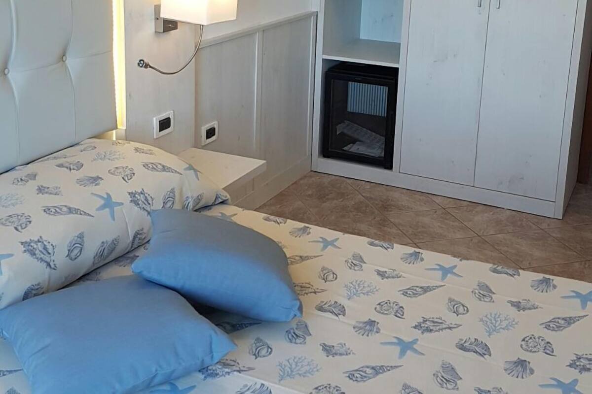 A bedroom with a bed, a wardrobe, and a bedside lamp.