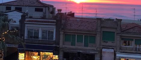 Ein Sonnenuntergang über einer Küstenstadt mit Häusern und Geschäften.
