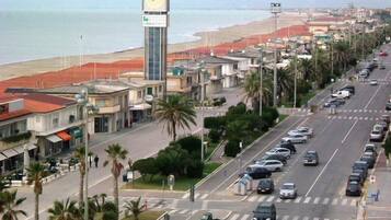 Una calle costera con edificios, una torre del reloj y coches aparcados.