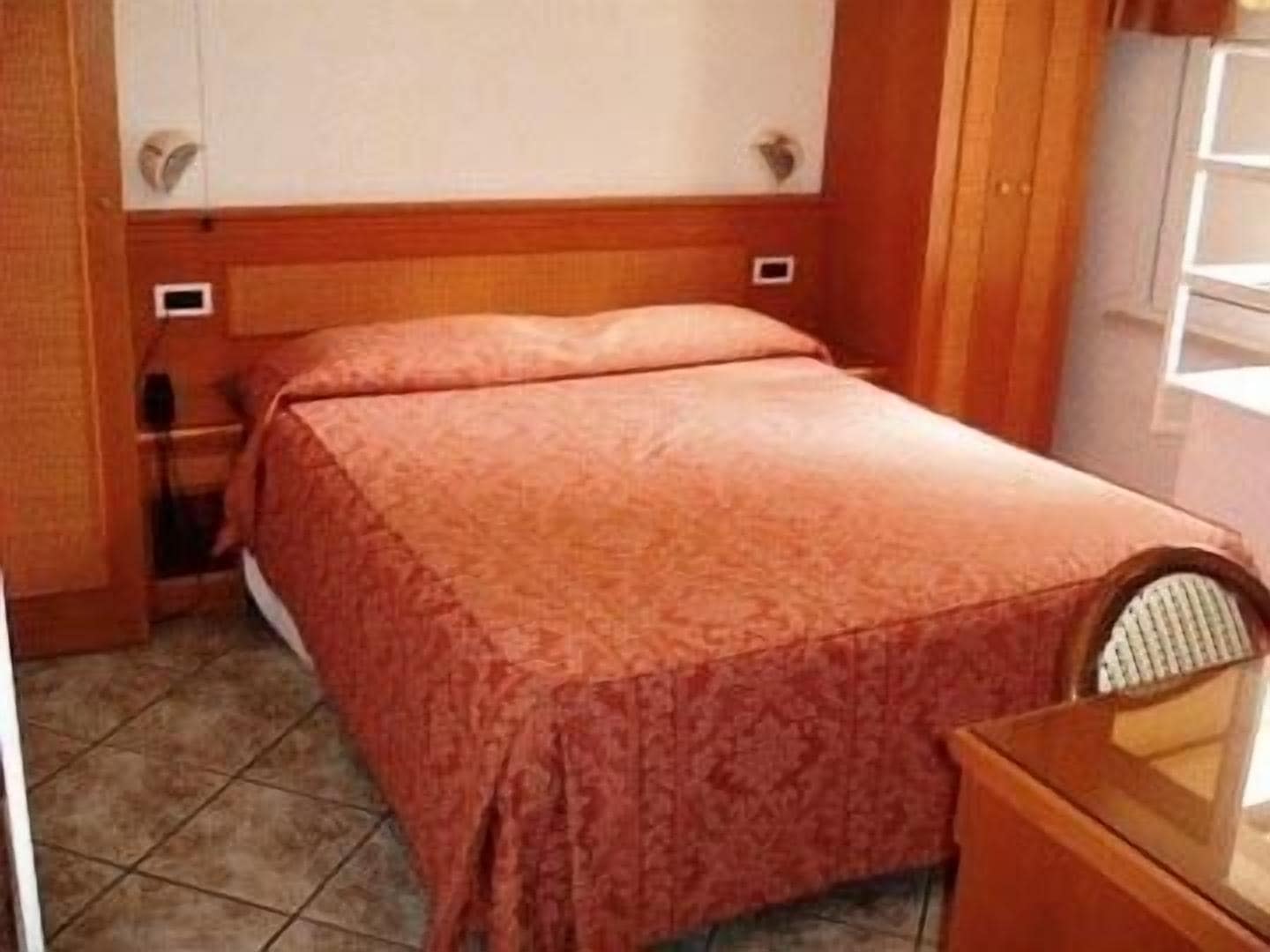 A small, neatly arranged bedroom with a bed, a nightstand, and a chair.
