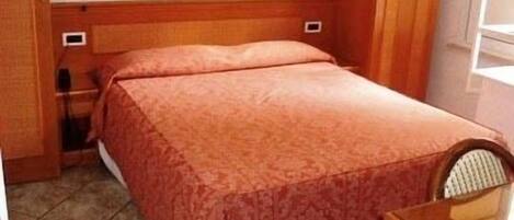 A small, neatly arranged bedroom with a bed, a nightstand, and a chair.