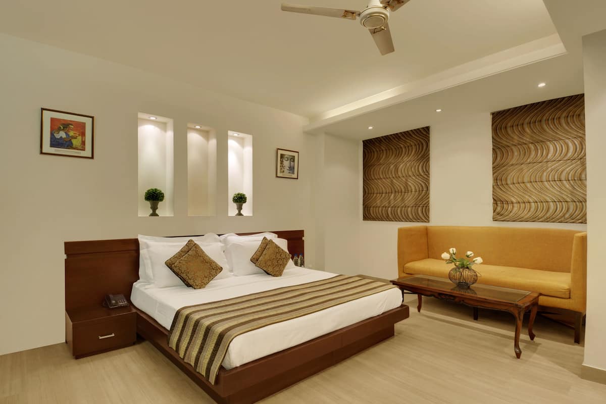Una habitación de hotel moderna con una cama grande, un sofá y un ventilador de techo.
