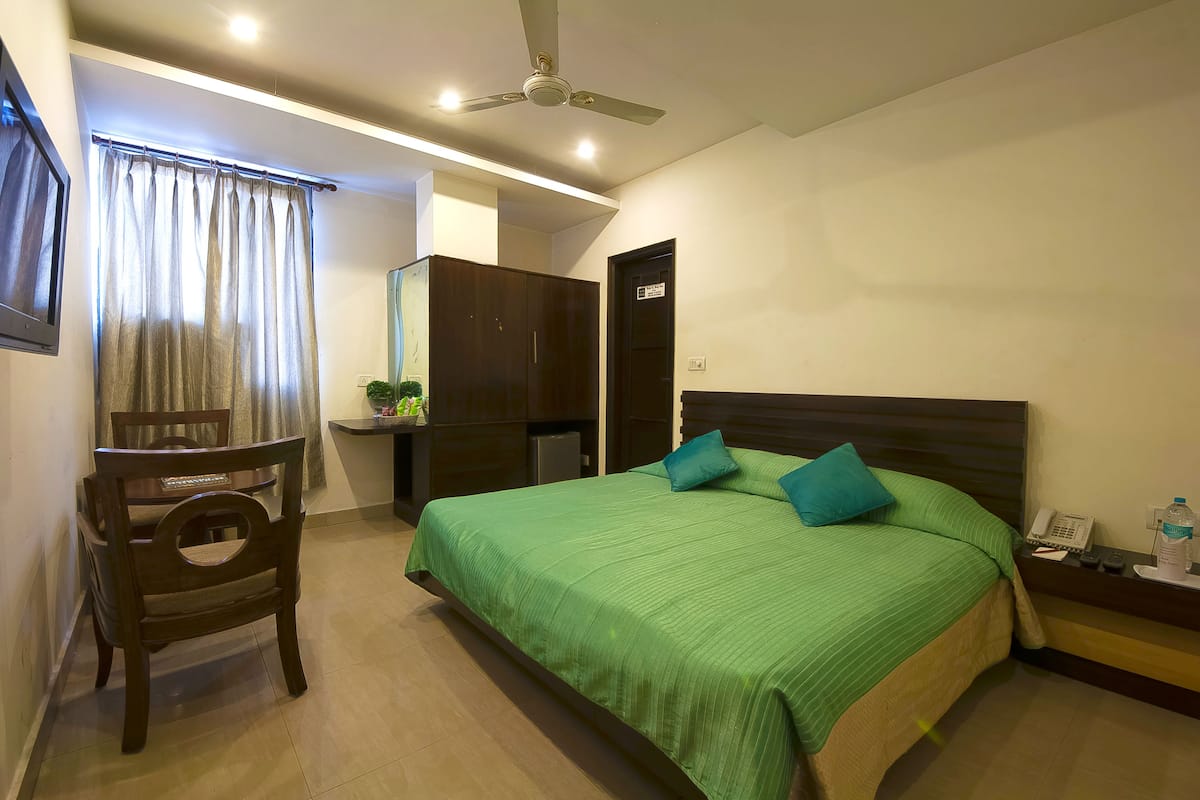 Un dormitorio con cama, una silla, un escritorio, un armario y un ventilador de techo.