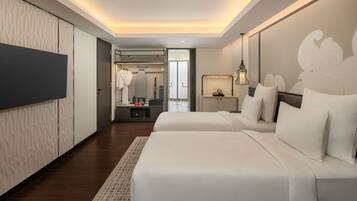 Quarto de hotel moderno com duas camas, um guarda-roupa, uma toucador com espelho e uma mesa de cabeceira com abajur.
