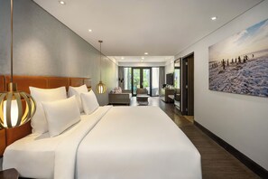 Moderni hotellihuone, jossa on suuri sänky, sohva, ruokailutila ja näkymä ulos.