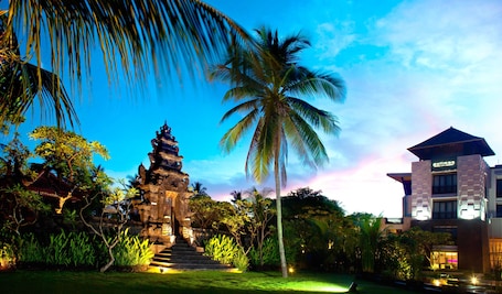 A traditional temple with a staircase leading up to it, surrounded by lush greenery and palm trees.