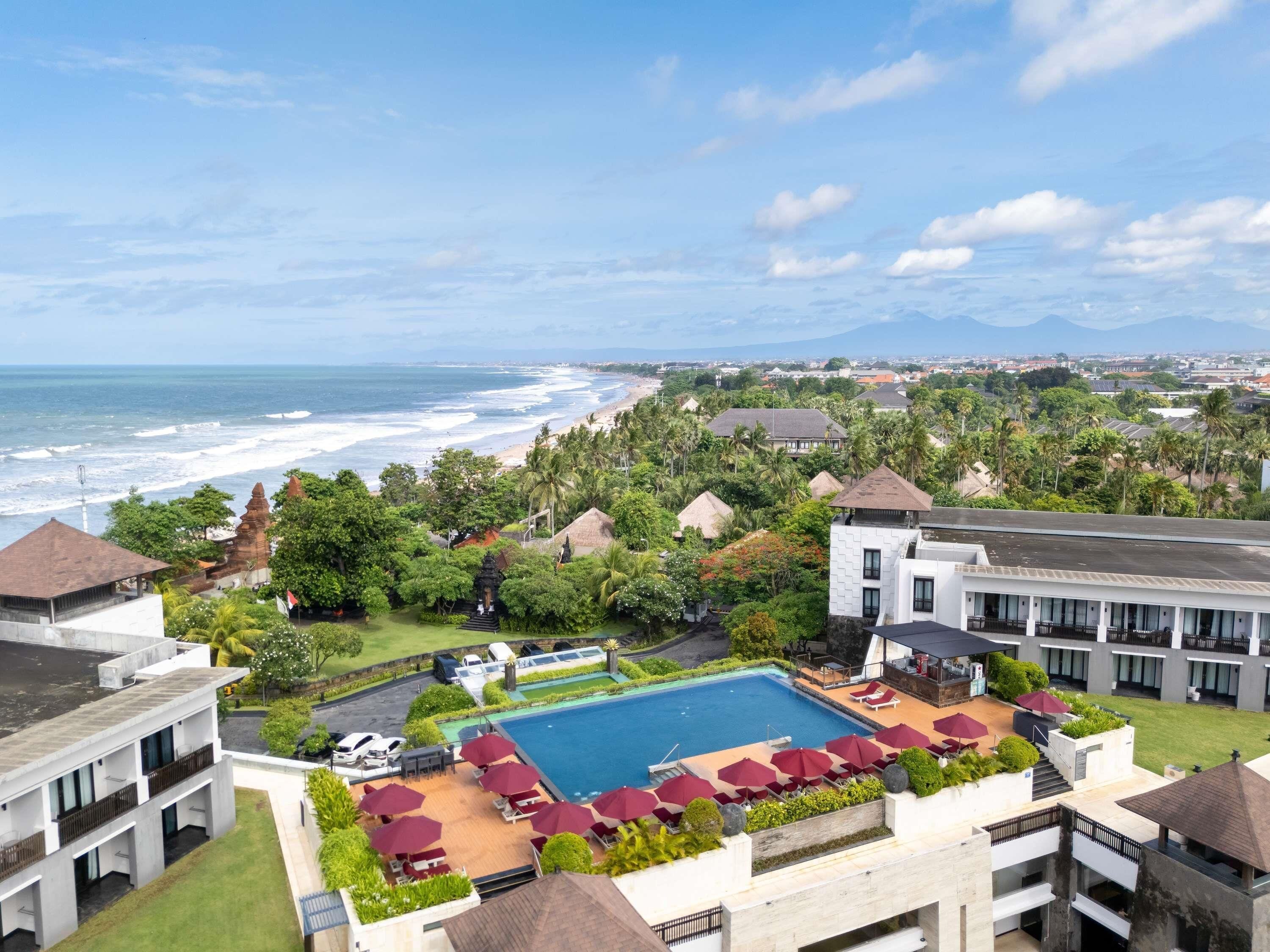 A resort with a swimming pool, beach view, and tropical landscaping.