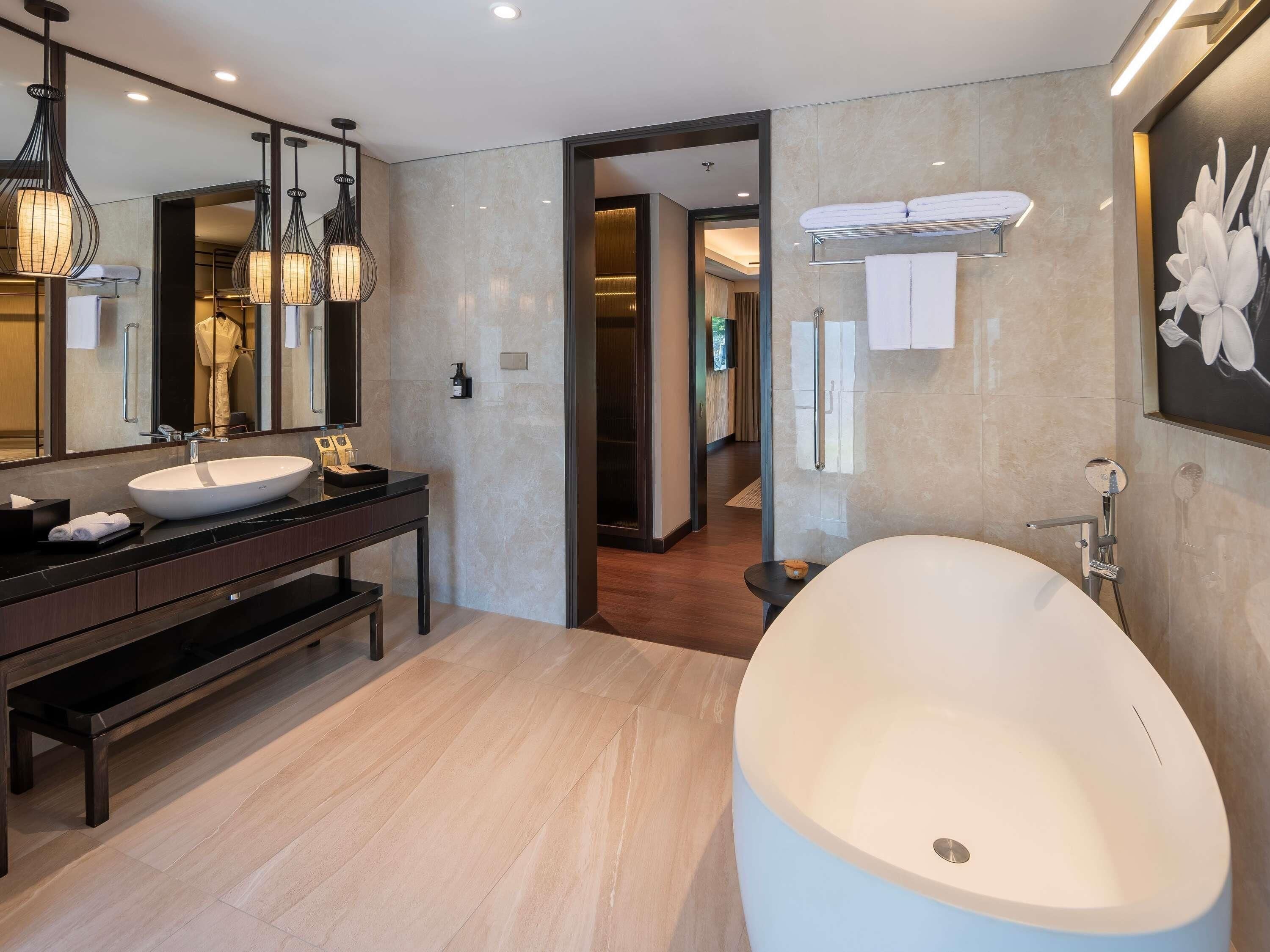 A modern bathroom with a large freestanding bathtub, a double vanity with two sinks, and a large mirror.