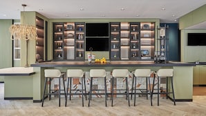 Una cocina moderna con barra, estanterías empotradas y un televisor de pantalla plana grande.