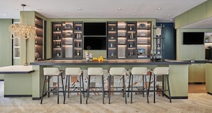 Una cocina moderna con barra, estanterías empotradas y un televisor de pantalla plana grande.