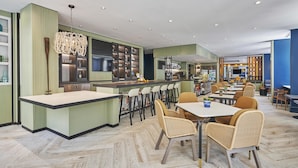 Un restaurante moderno con barra, mesas y una gran pantalla de televisión.