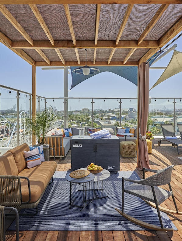 Una terraza en la azotea con sofá, mesa, armario y vistas de la ciudad.