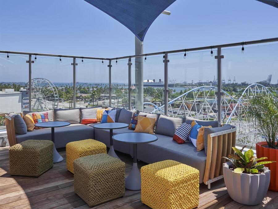 Una terraza en la azotea con zona de estar, vista a una noria y un paraguas grande que da sombra.