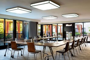 A conference room with a long table, chairs, and a TV screen.