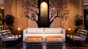 A modern lobby with a central sofa, two armchairs, a coffee table, and decorative wall art.