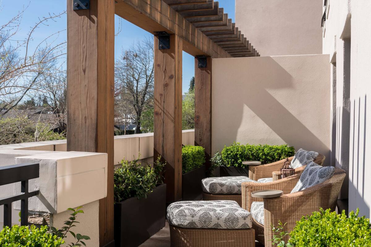 A covered outdoor seating area with wicker furniture and planters.