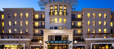 A hotel with a central atrium, multiple balconies, and storefronts on the ground level.