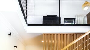 A modern interior with a staircase leading to a second floor, a kitchen area, and a bathtub. - Chimes Spa Retreat (Shadforth)