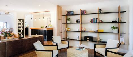 A modern hotel lobby with a reception desk, seating area, and a bookshelf.
