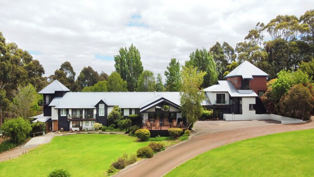A large, modern house with a spacious front yard, multiple entry points, and a driveway leading to a garage.