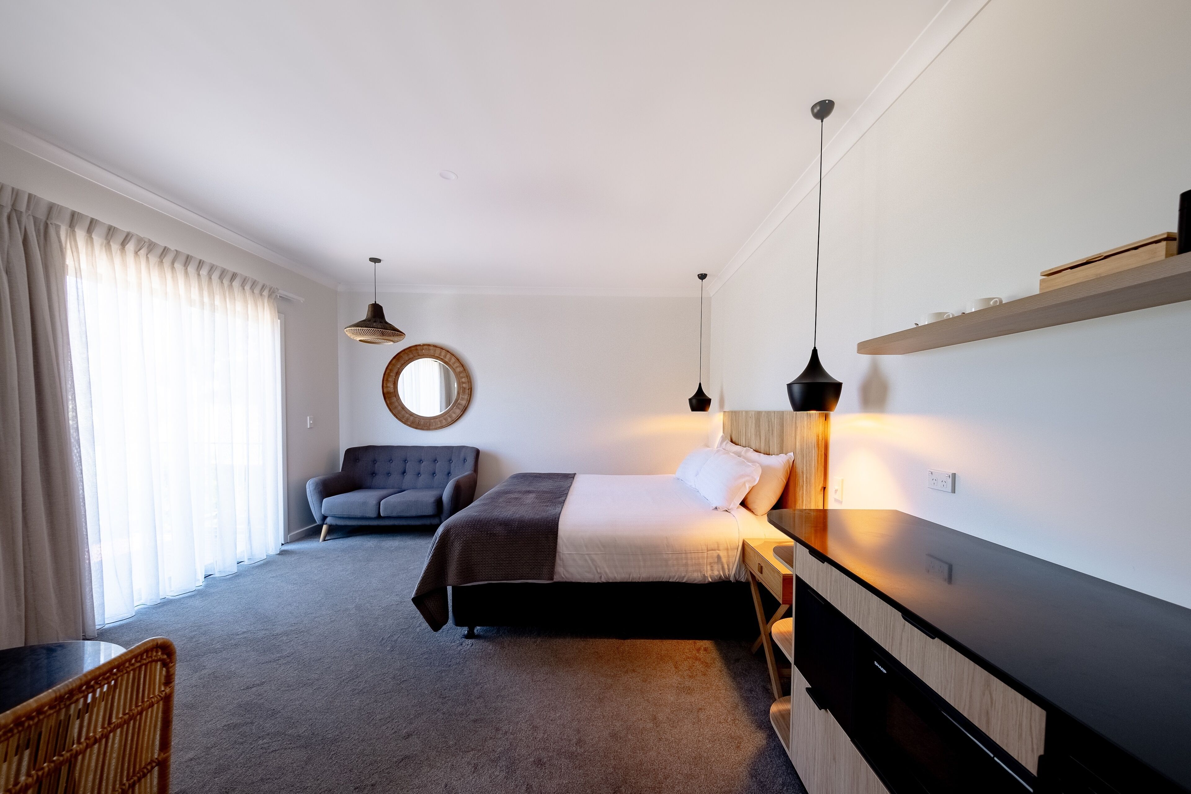 Et moderne soveværelse med seng, sengebord, lampe og stol.