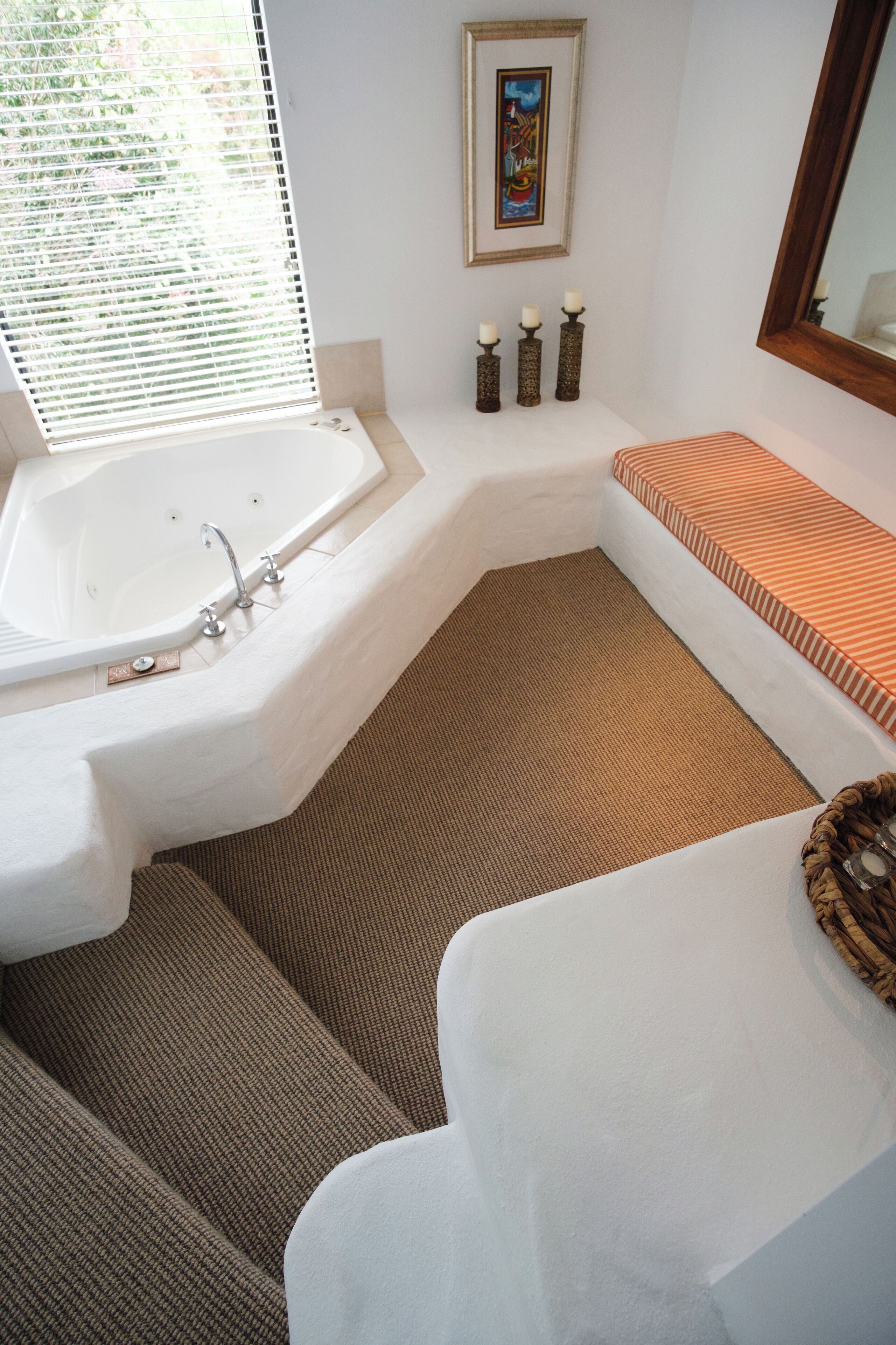 A modern bathroom with a freestanding bathtub, a bench, and a large mirror.