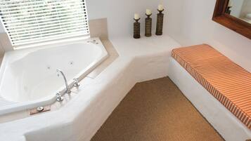 A modern bathroom with a freestanding bathtub, a bench, and a large mirror.