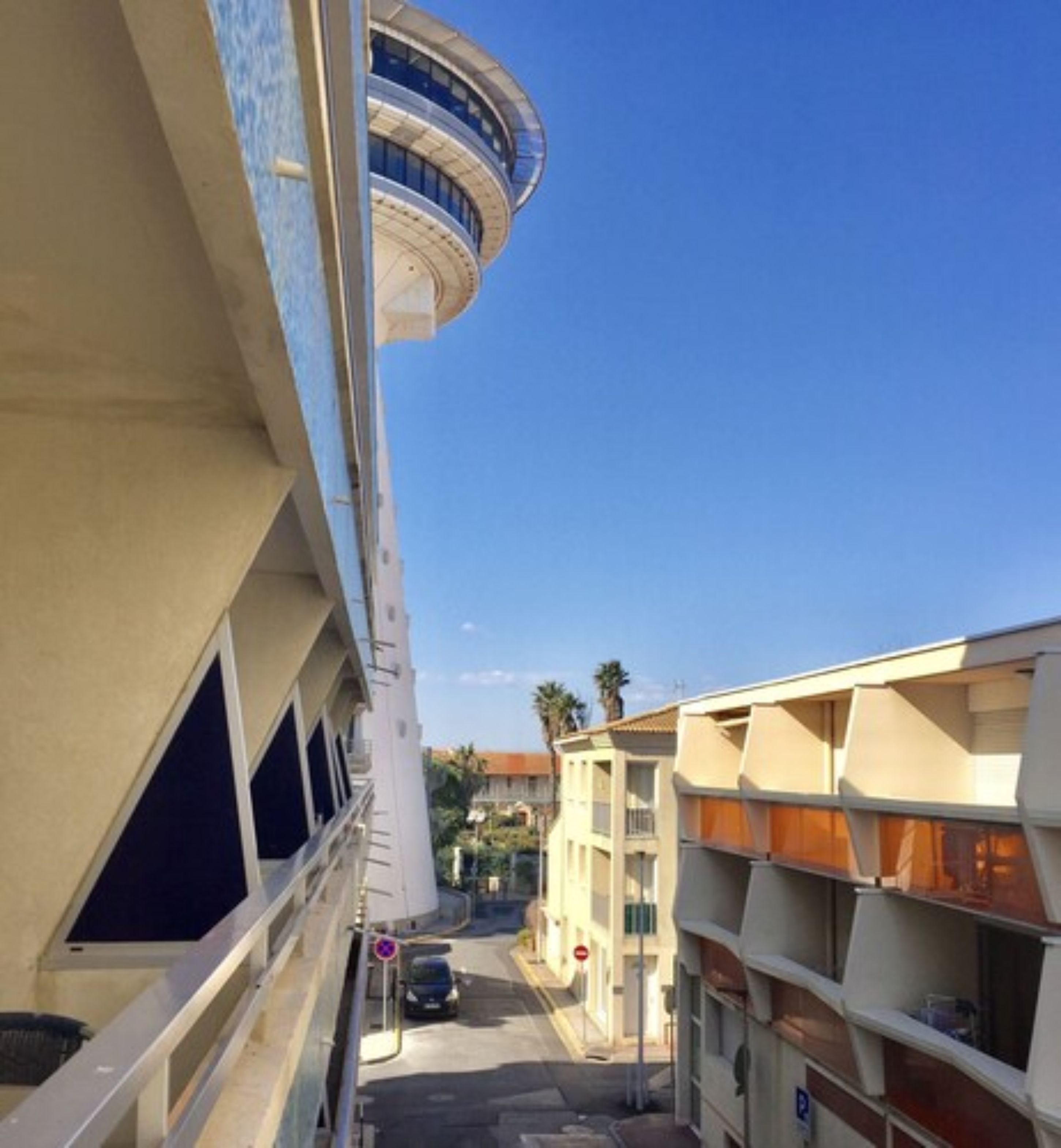 Una calle estrecha con un edificio que tiene una torre curva y balcones.