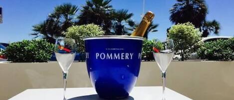 Un cubo azul para champán con la etiqueta "POMMERY" y dos copas de champán sobre una mesa.