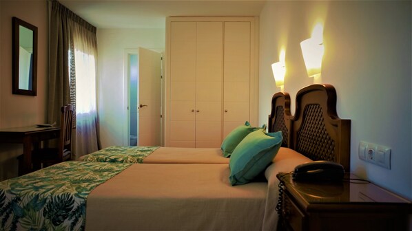 A hotel room with two beds, a desk, a chair, a telephone, and a wardrobe. - Hotel Ayamontino (Punta Umbría)