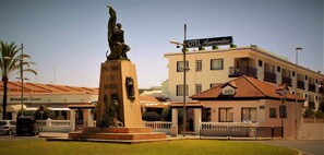 A hotel named 'HOTEL Ayamontino' with a statue in front, a restaurant named 'RESTAURANTE Carmen' to the left, and a building with a tiled roof. - Hotel Ayamontino (Punta Umbría)