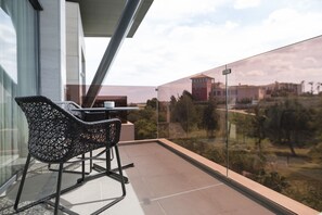 A balcony with a glass railing, a table, and two chairs.