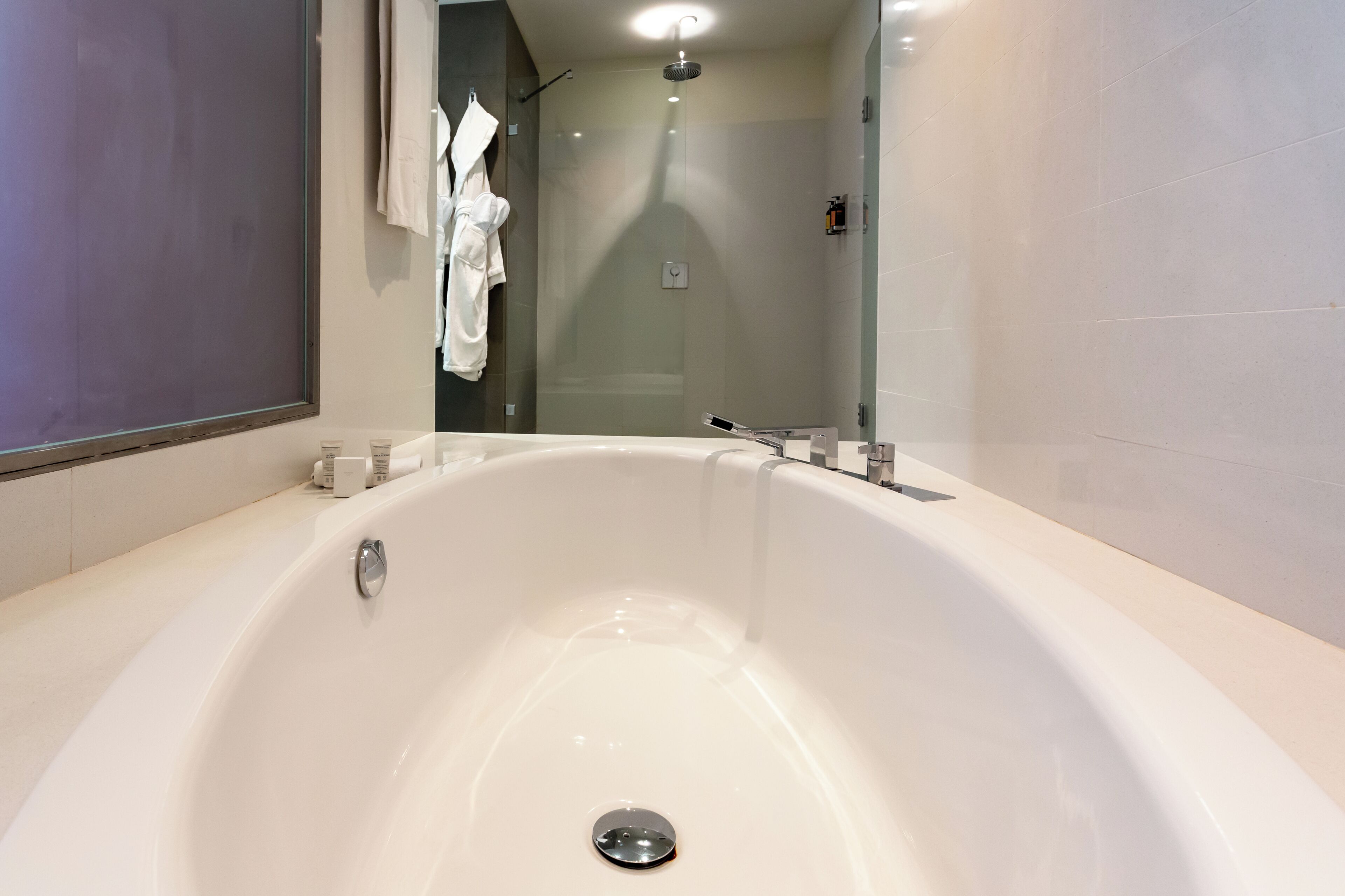 Une salle de bain moderne avec une grande baignoire, une douche et un miroir.