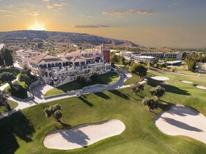 A large hotel with multiple buildings, a golf course, and a mountainous backdrop.