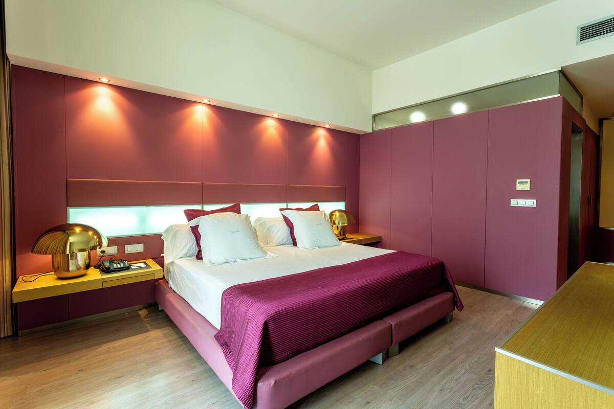 A modern bedroom with a large bed, bedside tables, and built-in lighting.