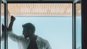 Un hombre de pie en un umbral, con vistas a una piscina y al océano.