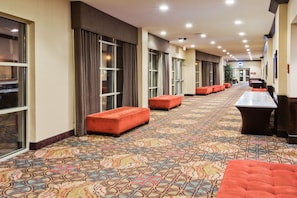 A hotel corridor with patterned carpet, seating areas, and a reception desk. - Crowne Plaza Anchorage Midtown by IHG (Anchorage)