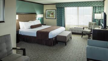 A hotel room with a bed, a desk, a chair, a television, and a window with curtains.