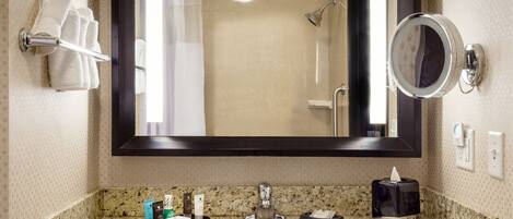 Une salle de bain équipée d’un lavabo, d’un miroir, d’un porte-serviettes et d’une zone douche.