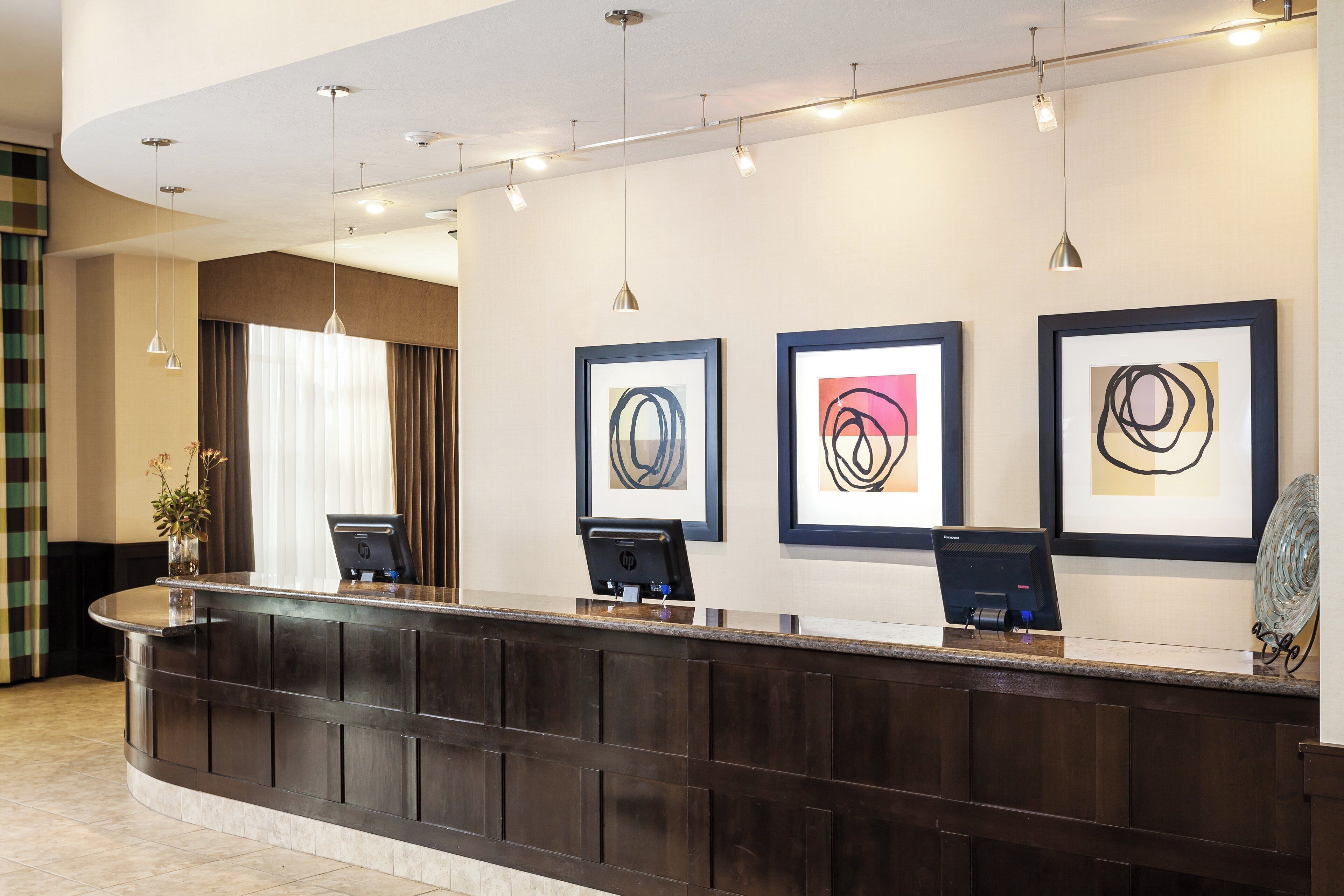 A reception desk with framed abstract art, a laptop, and a glass sculpture.
