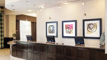 A reception desk with framed abstract art, a laptop, and a glass sculpture.