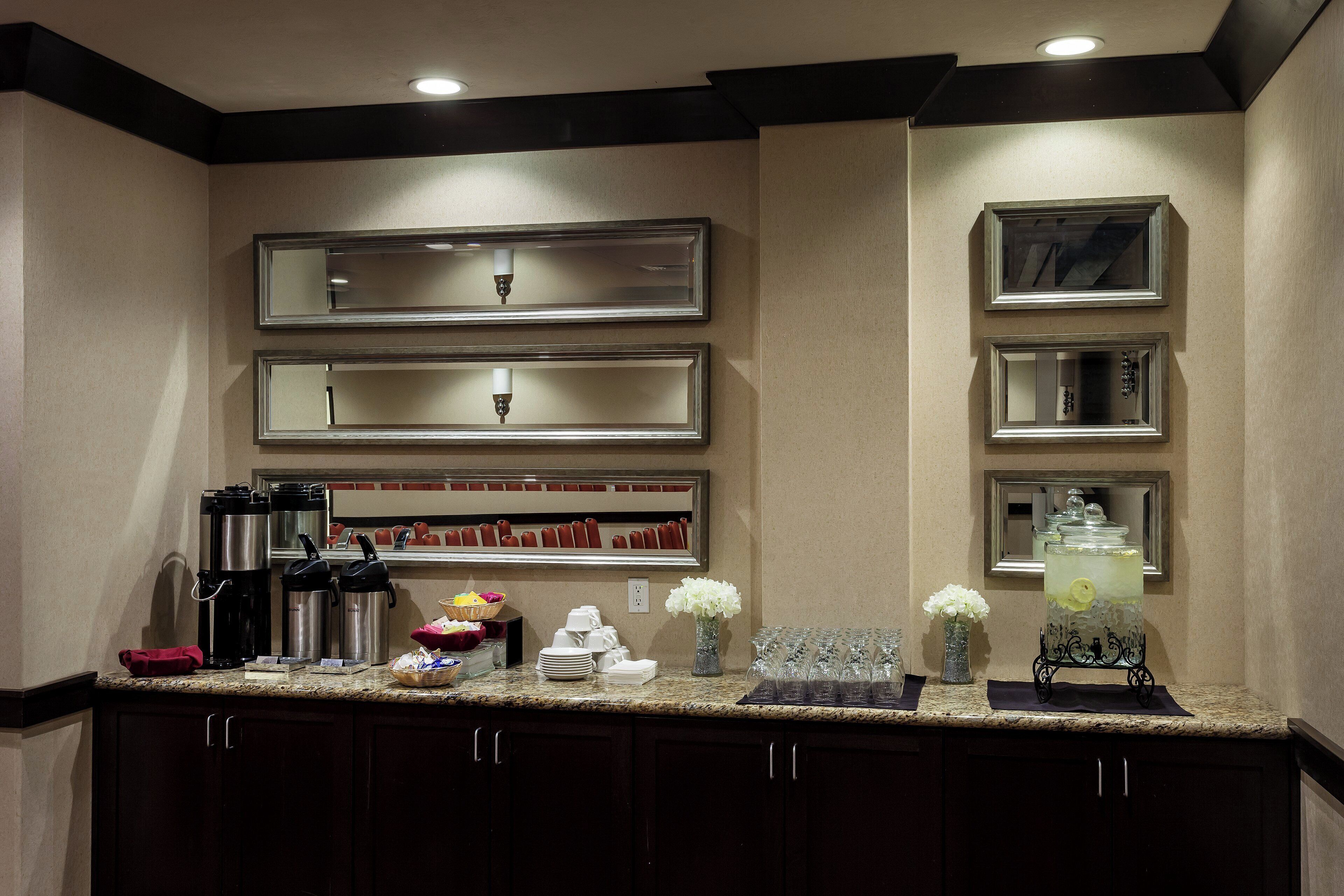 A hotel kitchen with stainless steel appliances, a buffet setup, and a decorative vase with flowers.