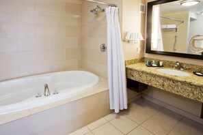 A bathroom with a bathtub, a sink, a mirror, and a shower curtain. - Crowne Plaza Anchorage Midtown by IHG (Anchorage)