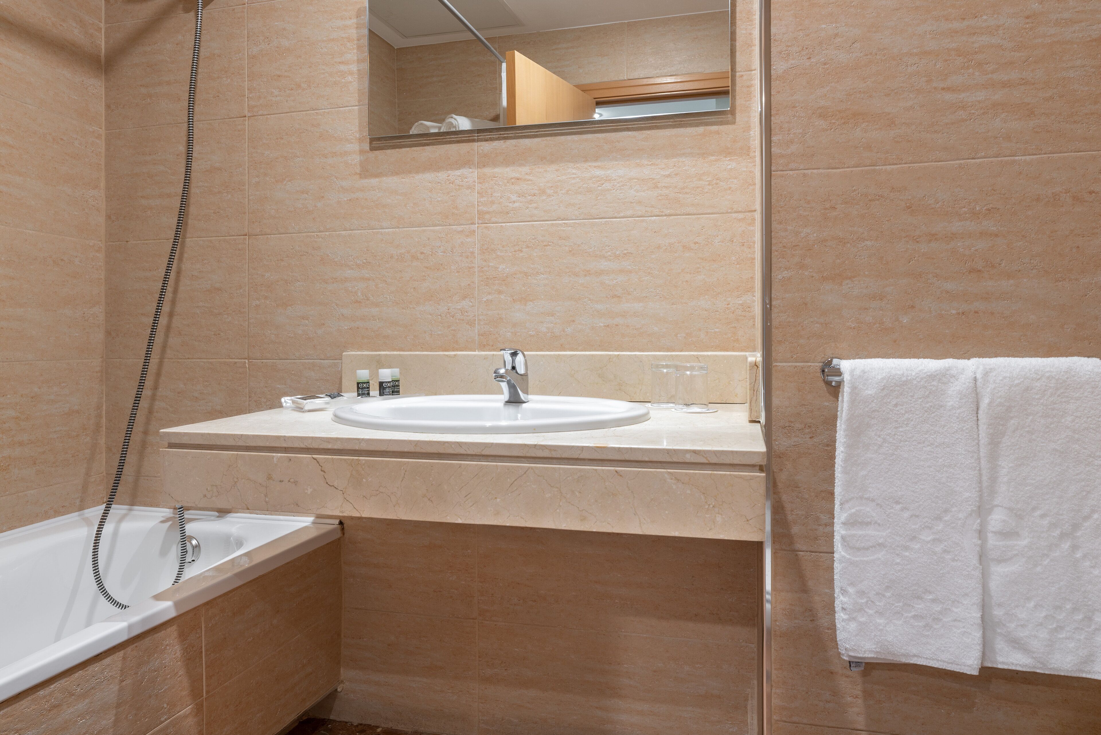 A bathroom with a bathtub, a sink, and a towel rack.
