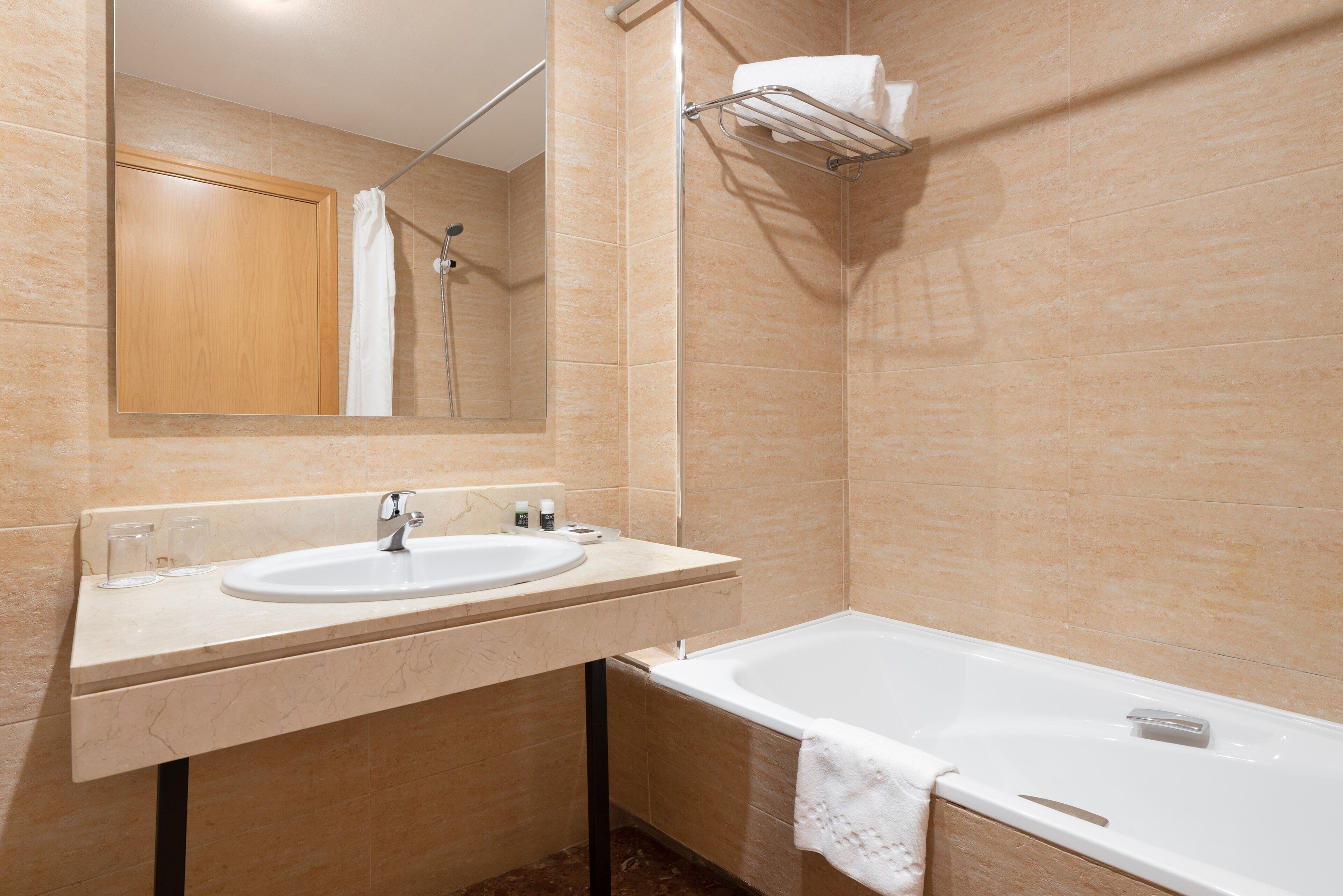 A bathroom with a sink, mirror, and bathtub.
